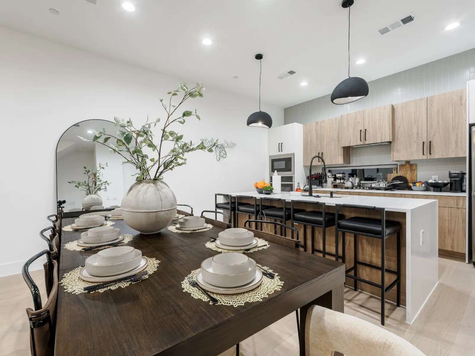 A modern kitchen with a spacious island that seats five and a beautifully set dining table for eight—perfect for cooking, hosting, and shared meals.