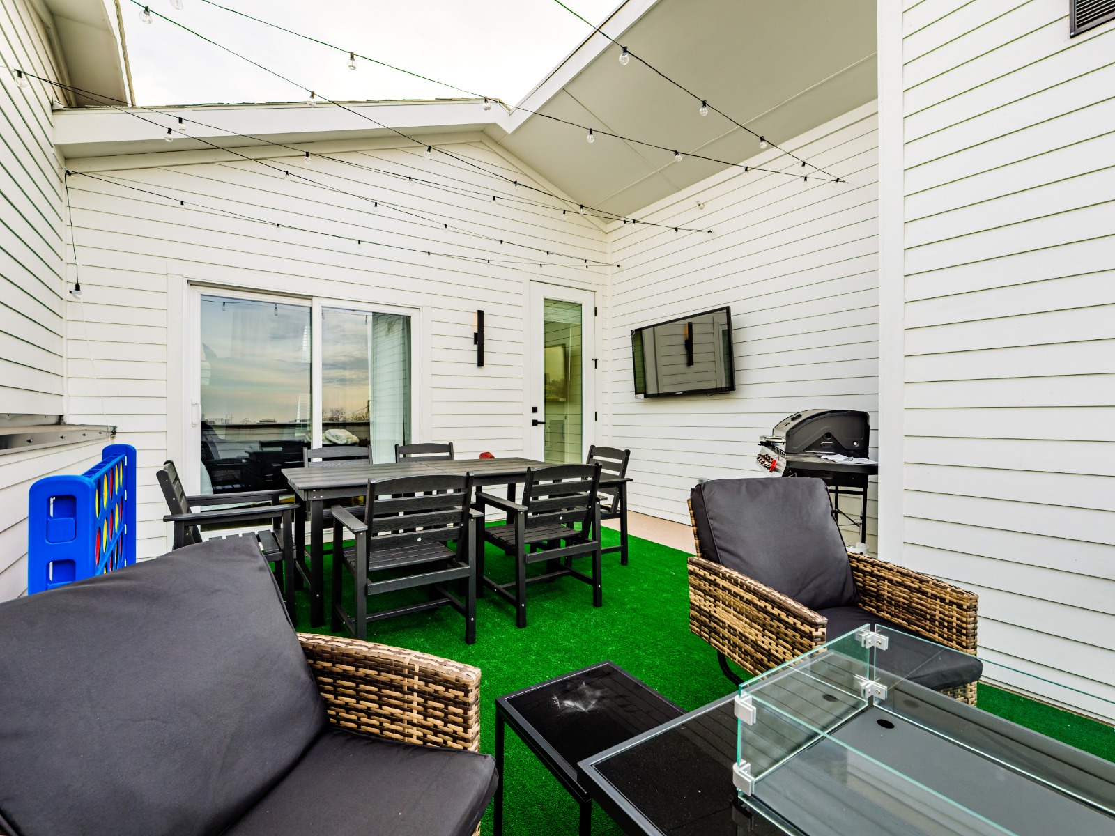 A roomy rooftop with dining for eight, a fire pit, grill, TV, and games—ideal for relaxing or hosting
