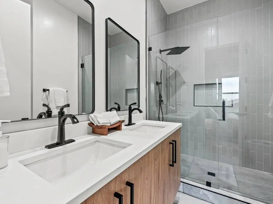 A sleek, modern bathroom with dual sinks, a glass walk in shower, and fresh towels for a comfortable, spa like experience.