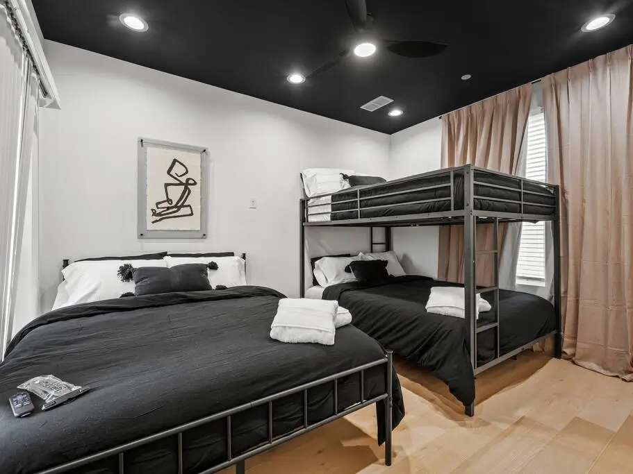 A bright, modern room with a queen bed, bunk beds, warm lighting, and plenty of space—perfect for families or groups.